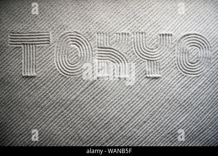 Japanese Zen garden raked with the word TOKYO in capital letters in textured white sand Stock Photo