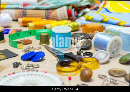 various accessories for sewing and needlework lie on the table close-up with blurred background and foreground Stock Photo