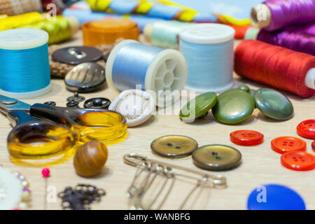 various accessories for sewing and needlework lie on the table close-up with blurred background and foreground Stock Photo