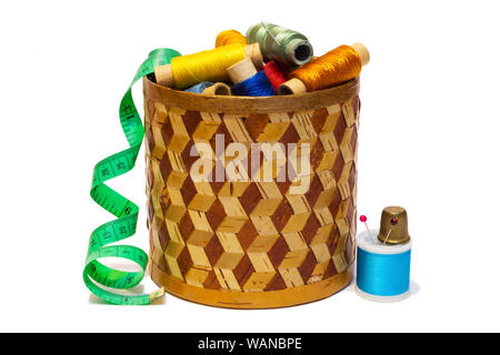 braided manually birchbark cylindrical box with spools of colored threads and dressmaker's measuring tape, isolated on white background Stock Photo