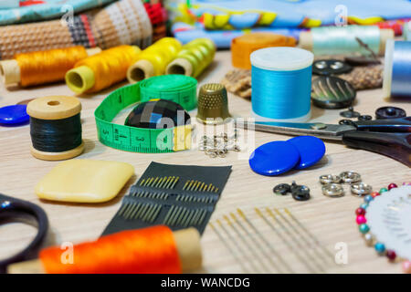 various accessories for sewing and needlework lie on the table close-up with blurred background and foreground Stock Photo