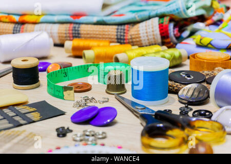 various accessories for sewing and needlework lie on the table close-up with blurred background and foreground Stock Photo