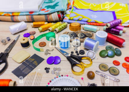 various accessories for sewing and needlework lie on the table close-up with blurred background and foreground Stock Photo