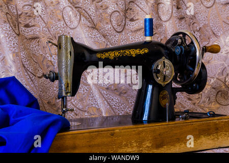 still life with antique sewing machine and and bright blue fabric Stock Photo