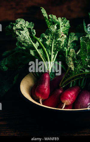 Bowl of homegrown red radish on wooden table Stock Photo