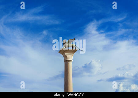 Saint Mark Winged Lion medieval statue, a symbol of the Old Venice Republic, at the top of an ancient column among clouds Stock Photo