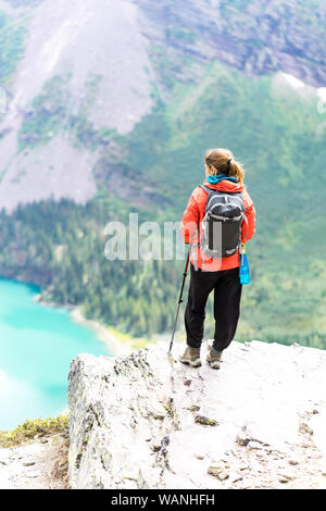Hiker is standing on a cliff looking at the lake in GlacierNP, Montana