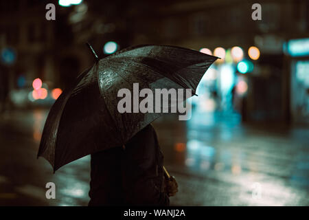 Girl covered with an umbrella on a rainy street night black Stock Photo