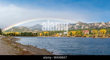 A rainbow forms over Lake Estes, The Stanley Hotel, Lake Estes 9-Hole Golf Course and downtown Estes Park as fall colors add color to the shoreline in Stock Photo