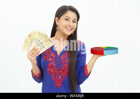 Young woman showing five hundred rupees banknote and holding pie chart Stock Photo