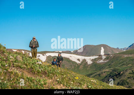 Three hikers come up over a ridge in the tundra along the Mount Chapin Trail in Rocky Mountain National Park, Colorado. Stock Photo