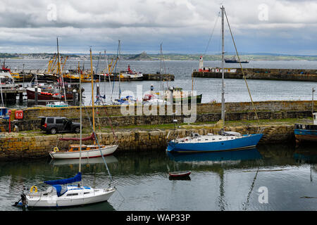 Fishing and sail boats in Newlyn harbour with St Michaels Mount at Marazion and Longrock Penzance on Mounts Bay Cornwall England Stock Photo