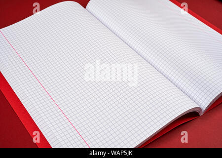 open notebook with checkered pages on a red background Stock Photo