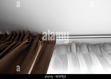 Brown curtains and white tulle on a rail with a white ceiling. Curtain interior decoration in living or sleeping room. Comfortable live in your own ho Stock Photo
