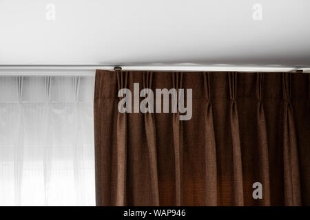 Brown curtains and white tulle on a rail with a white ceiling. Curtain interior decoration in living or sleeping room. Comfortable live in your own ho Stock Photo