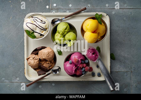 Assorted flavors and colors of gourmet Italian ice cream served on steel table. Mango, chocolate, green matcha ice cream Stock Photo