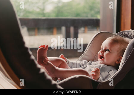 6 months baby girl sitting in a car seat near the panoramic window Stock Photo