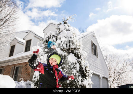 boy surrounded by snow getting hit with snowball from behind by boy Stock Photo