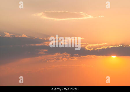 The sun peaks out from behind a cloud before sunset near Alamosa, San Luis Valley, Colorado. Stock Photo