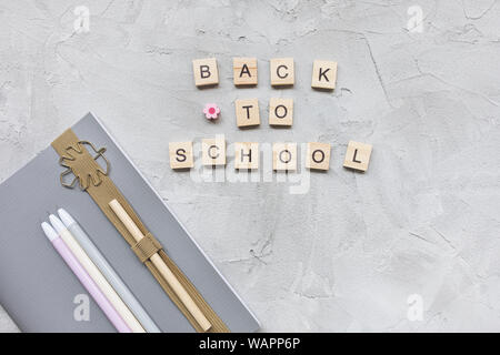 Words BACK TO SCHOOL, notebook, pencil and pens on a gray background. Education or studying concept, flat lay, top view, social media hero header temp Stock Photo
