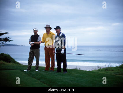 Three men standing with golf clubs on a golfing green. Stock Photo