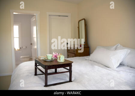 Wooden bed tray with a teapot sitting on a bed. Stock Photo