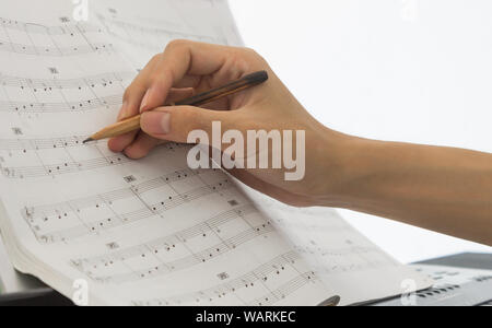 Hand of Piano Player is Writing Notes on Piano Staff or Sheet Music by Old Pencil Stock Photo