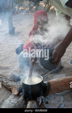 Old lady cooking a pot of Nshima, a thick porridge made from finely ground corn meal, Mwandi, Zambia, Africa. Stock Photo