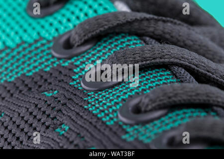 A fragment of a green sneaker with black laces close up. Sneaker texture Stock Photo