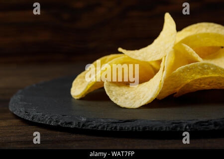 Salty delicious potato chips on stone board. copy space Stock Photo