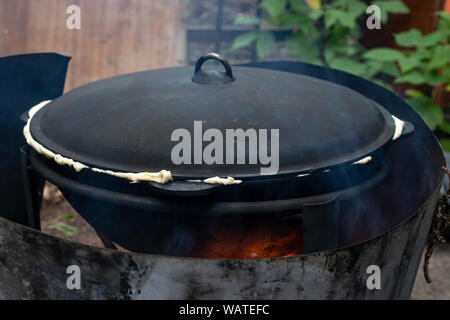 cast iron cauldron or cooking pot on fire outdoors Stock Photo