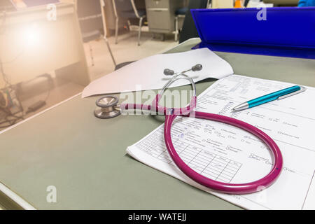 The doctor is waiting for the patient in the examination room.Doctor's desk with patient history and stethoscope is placed. Stock Photo