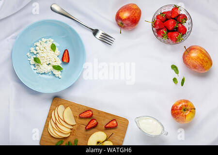 Healthy dessert with cream, with strawberries, apples and cottage cheese on a white tablecloth. overhead view. Cpoy space Stock Photo