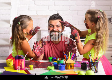 Girls drawing on man face skin with colorful paints Stock Photo