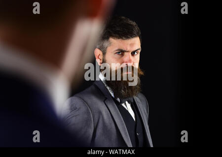 Businessmen, business partners meeting on black background. Businessmen look at each other with judgment, copy space. Eye contact concept. Business Stock Photo