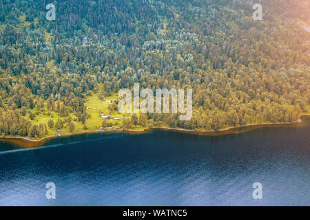 Small alone house in the Teletskoe Lake at the Altai Mountains near the lake surrounded by green trees on a sunny summer day Stock Photo