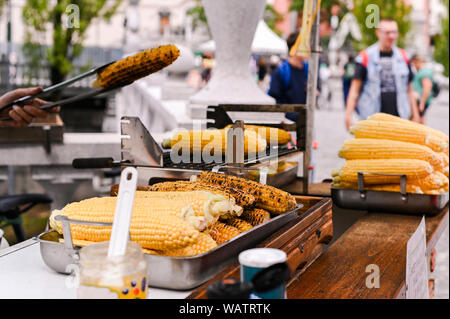 Grilled corn. Fast food in the city center for tourists. Selling food on the street. Hands in the frame of the buyer and seller Stock Photo