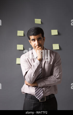 Businessman thinking with adhesive note on wall Stock Photo