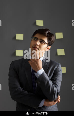 Businessman thinking with adhesive note on wall Stock Photo