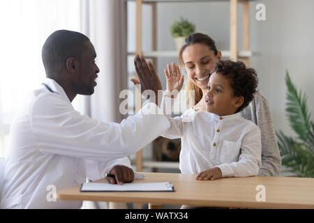 Happy cute child boy give high five to african pediatrician Stock Photo