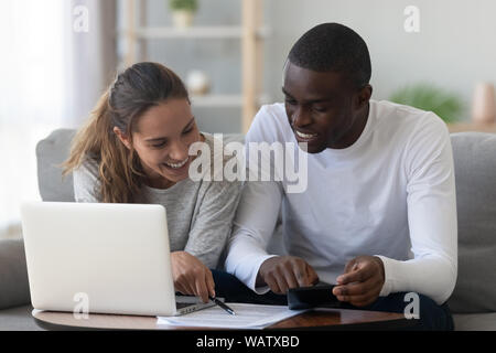 Happy smiling mixed race couple calculating domestic bills at home Stock Photo