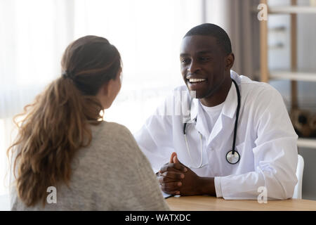 Smiling black male doctor listening female patient at medical meeting Stock Photo