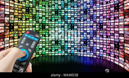 Image of large screen with many multi-colored channels, hands of man with remote control on blank black background Stock Photo