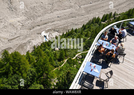 Tourists at outdoor café restaurant of Montenvers Railway station with the entrance of the Ice Cave in the crevasse, Chamonix-Mont-Blanc, Alps, France Stock Photo