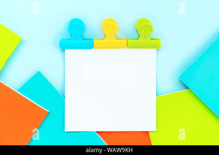 A white sheet for writing attached by three multi-colored stationery clips  Stock Photo