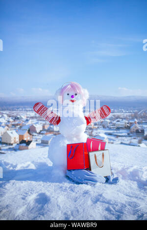 New year snowman from white snow with shopping bag. Happy holiday and celebration. Winter activity and party. Snowman in pink wig and mittens with gif Stock Photo