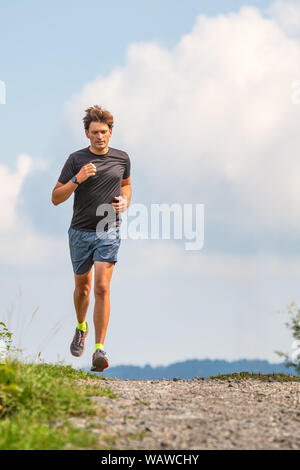 Young athlete man runs on dirt road Stock Photo