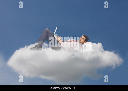 Businessman lying on clouds and using laptop concept cloud computing Stock Photo