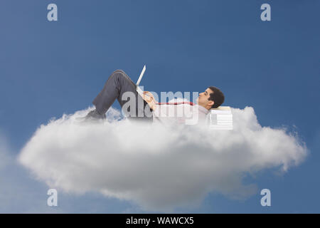 Businessman lying on clouds and using laptop concept cloud computing Stock Photo
