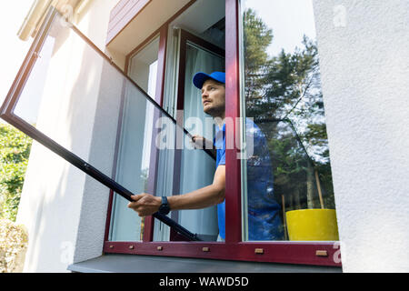 handyman installing mosquito net mesh screen on house window Stock Photo